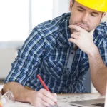 Builder with laptop, working on floorplans