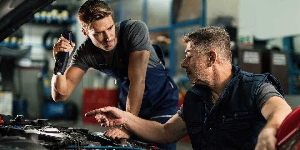 Two mechanics looking under the hood of a car