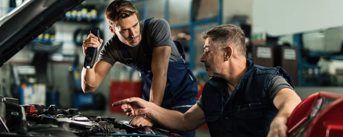 Two mechanics looking under the hood of a car