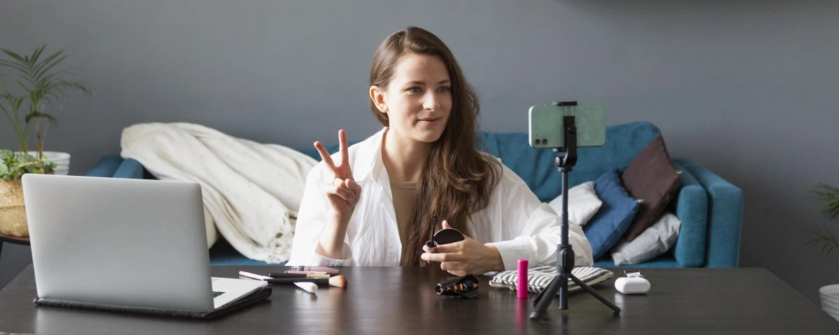 Lady filming in her living room with her smart phone on a tripod on her coffee table.