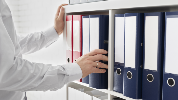 Hand reaching for a file on a shelf full of files