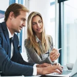 man and woman in office looking at a laptop together