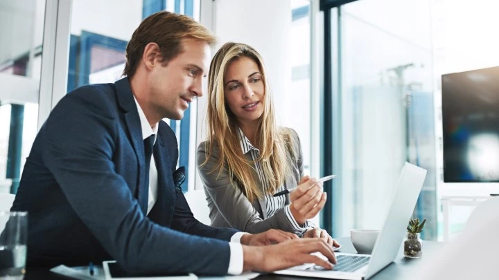 man and woman in office looking at a laptop together