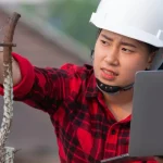 Builder working in the field whilst also holding a laptop