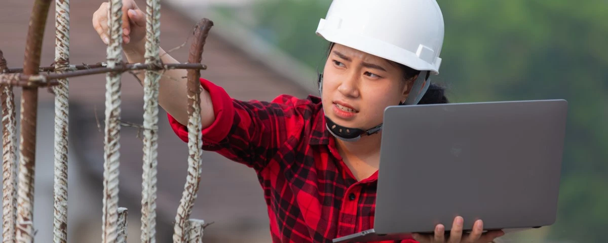 Builder working in the field whilst also holding a laptop