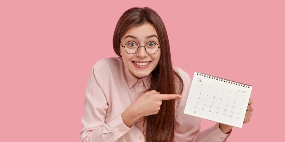 Lady grinning pointing at calendar