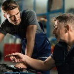 Two mechanics looking under the hood of a car