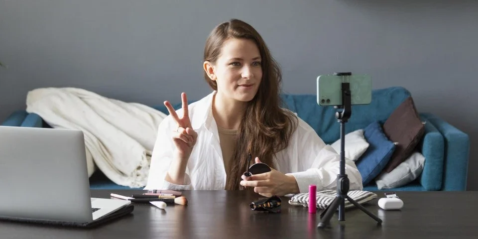 Lady filming in her living room with her smart phone on a tripod on her coffee table.