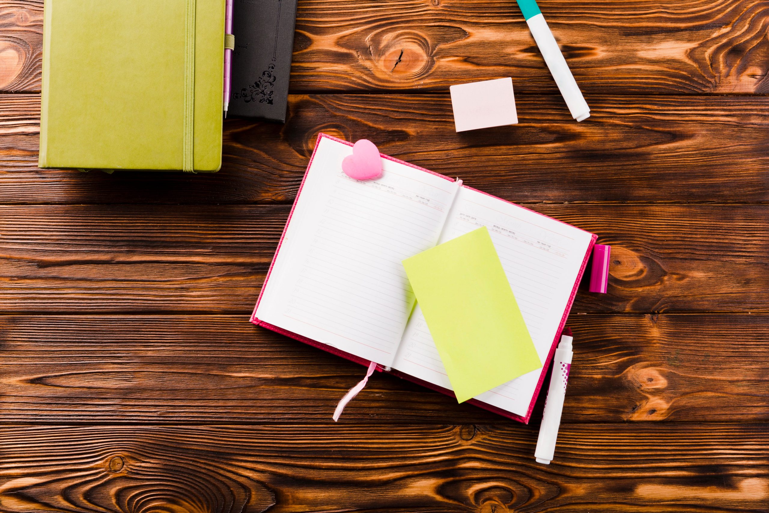 A notebook laid out on a desk with post-its and pens.